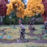 Miniature figure in a garden setting with trees and flowers in the background
