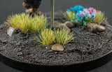 Model landscape with grass, rocks, and colorful flowers on a round base.