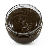 Jar of dark brown paste on a white background