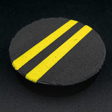 Round black object with yellow stripes on a dark background