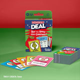 Monopoly Deal: How the Grinch Stole Christmas! card game box shown upright with several colorful cards fanned out in front and a stack of cards to the right, on a green surface against a red background. Visible brands include Monopoly and Hasbro Games.