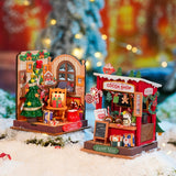 Two miniature Christmas-themed shops with festive decorations on a snowy background.