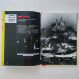 Open book with black and white photograph of a castle on a hill and text on a white background