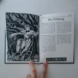 Open book with black and white illustration and text on a white background