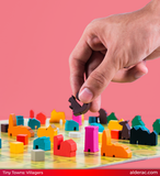 Hand playing with colorful board game pieces on a pink background