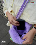 Person holding a purple furry bag with a phone inside, wearing a white shirt.