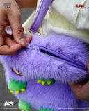 Purple plush toy with a zipper being opened by a hand, with a blurred background.