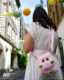 Person wearing a white dress with a pink fluffy bag on a street with colorful balloons.