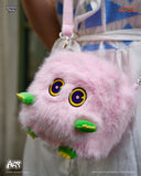 Pink fluffy bag with cartoonish face and green accents, held by a person wearing a blue and white striped shirt.
