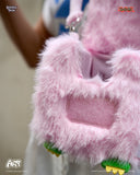 Close-up of a pink fluffy bag with green accents, featuring a brand logo.