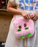 Person holding a pink plush bag with cartoon face design