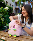 Woman holding a pink plush toy with green accents outdoors