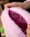 Close-up of a pink plush toy with a zipper, held by a hand.
