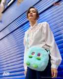 Person holding a blue plush bag with cartoon face design against a blue background