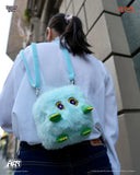 Person wearing a plush backpack with cartoonish face design in an urban setting