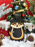 A black dog-shaped bag with a cartoon dog face design in beige, orange, and black, featuring a top strap labeled 'Globion'. The bag is styled in a festive Christmas setting with a decorated tree, red backdrop, and faux snow.