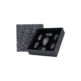 Set of silver jewelry pieces in a black box with geometric patterned lid on a white background