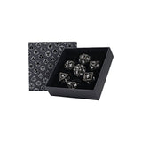 Set of dice in a black box with a patterned card on a white background