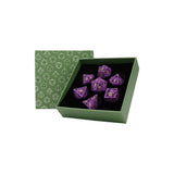 Purple polyhedral dice set in a green box with geometric pattern