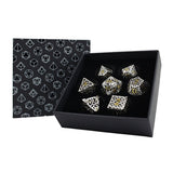 Set of silver dice with gold accents in a black box with geometric pattern, next to a matching black box.