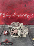 Metal dice shaker with intricate design on a red leather surface with engraved text, Lethal Shadows logo visible.