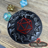 Black and red gaming die with dragon design on a wooden surface, featuring 'Lethal Shadows' branding.