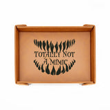 Brown leather tray with black text 'TOTALLY NOT A MIMIC' on a white background