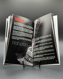 Open book with black and white illustration and text on a gray background