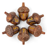 Six acorn-shaped dice with engraved gold numbers 1 through 6, arranged in a circle on a white background.