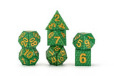 Set of green polyhedral dice with gold numbers on a white background