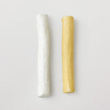 Two cylindrical candles, one white and one yellow, on a light gray background