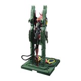 A pink and white mecha figurine mounted on a green display stand with a matching base, photographed against a plain white background.