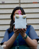 Person holding a plush toy in front of their face against a neutral background