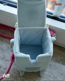 Small blue plush cube box with pink strap on a neutral background