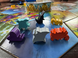Colorful game pieces on a board game with various game cards in the background