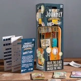 Whiskey Journey escape room game packaging on a wooden surface with gray background