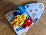 Three toy figures on a white base with colorful designs on a wooden surface