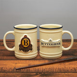 Two ceramic mugs with 'Butterbeer' branding on a wooden surface.