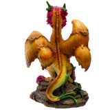A fantasy dragon figurine with golden-orange wings and body, green and yellow accents, pink flowers on its head and around the base, standing on a rocky pedestal against a plain white background.
