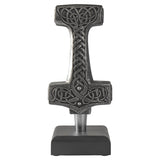 A Celtic-style hammer figurine with intricate knotwork carvings, displayed on a black stand against a plain white background.