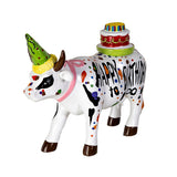 A white ceramic figurine of a cow decorated with colorful paint splatters, a green party hat, and a pink collar, with a small birthday cake on its back and the text 'HAPPY BIRTHDAY to co' written on its side, set against a plain white background.