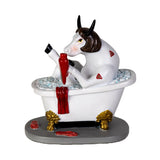 A novelty figurine of a cow sitting in a bathtub with red blood splatters, holding a bloody syringe, set on a gray base with gold claw feet.