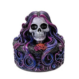 Decorative skull figurine with purple hair and a rose on a white background