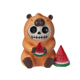 Skull-faced bear figurine holding watermelon slices on a white background
