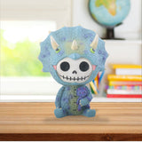 Blue dinosaur toy with skull design holding a purple creature on a wooden surface.