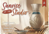 Board game cover titled 'Sunrise at the Studio' with a clay vase and tools on a wooden table.