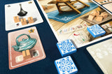 Board game setup with cards and tiles on a blue surface
