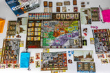 Board game components including a map, cards, and pieces on a white surface.