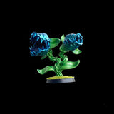 Glowing blue and green flower-like figurine on a black background
