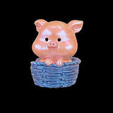 Pink pig figurine sitting in a blue basket on a black background